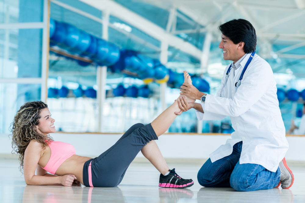Gym doctor with a patient checking her ankle