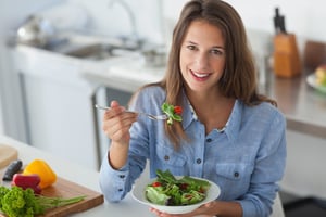 Pretty woman eating a salad in the kitchen