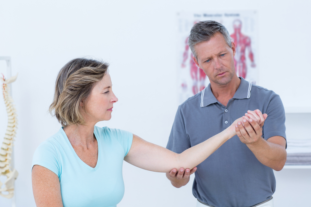 Doctor stretching his patients arm in medical office