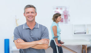 rsz_doctor_smiling_at_camera_while_his_patient_standing_with_crutch_in_medical_office-1